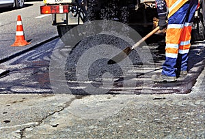 The road builder pours fresh asphalt and renews a part of the road for repair