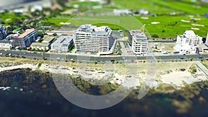 Road, buildings and coastal city on drone for commute transportation, sea view property or infrastructure location. Cars