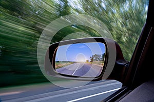 Road in car side-view mirror