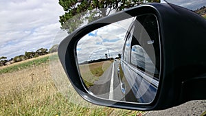 Road in car side-view mirror