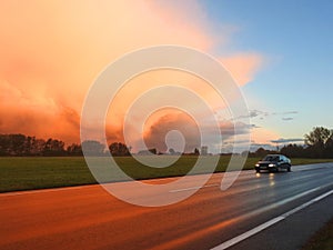 Road, car and vivid sky before rain in sunrise time, Lithuania