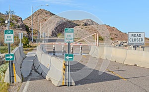 Road closed and barricaded on Davis Dam. Bike Access Signs showing bicycling and walking allowed on the Davis Dam road, on the bor