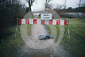 A road is closed with a barrier and a sign with the German inscription: Flood