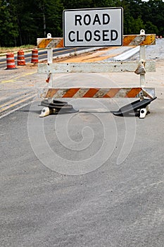 Road Closed sign on a battered traffic barricade, safety barrels and roadway construction, creative copy space