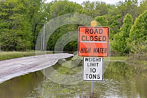Road closed sign and high water flooding roadway