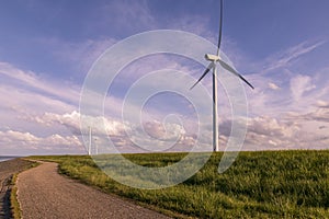 Road on coast near sea and wind electric mill