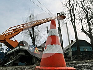 Road cone used during spring pruning of trees with bucket truck and aerial device. Pollarding trees among electricity lines,
