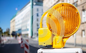 Road construction concept. Orange warning light. Blur city background, space