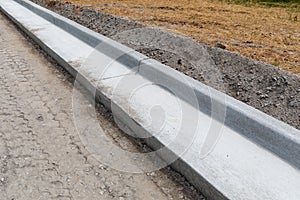 Road construction details, extruded concrete curb beside freshly prepared road bed