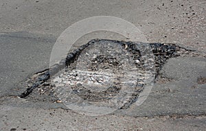 Road construction or driveway pothole repair: repairing an asphalt road with pothole method by cleaning and reshaping the pothole