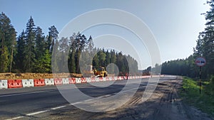 Road construction equipment is being used to reconstruct an ordinary highway into an expressway. There are mixed forests along the