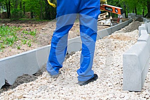 Road construction and installation of curbs in the Park, the feet of the worker in blue uniform