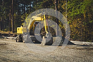 road construction machines. Road repair, asphalt laying. Yellow wheeled excavator on the background of the forest