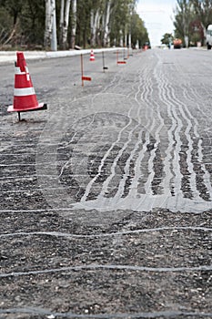 Road construction or repair - laying a new layer of asphalt, marking the level for increased accuracy and warning signs cone