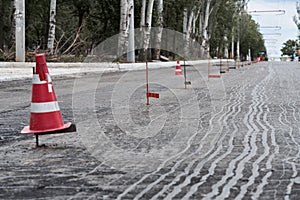 Road construction or repair - laying a new layer of asphalt, marking the level for increased accuracy and warning signs cone