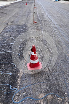 Road construction or repair - laying a new layer of asphalt, marking the level for increased accuracy and warning signs cone