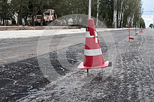 Road construction or repair - laying a new layer of asphalt, marking the level for increased accuracy and warning signs cone