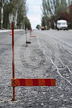 Road construction or repair - laying a new layer of asphalt, marking the level for increased accuracy and warning signs cone