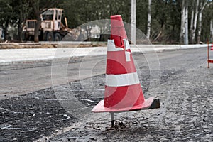 Road construction or repair - laying a new layer of asphalt, marking the level for increased accuracy and warning signs cone