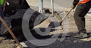 Road Construction and Repairing Works. Worker Leveling Fresh Asphalt on a Road Construction Site. Worker Using Asphalt