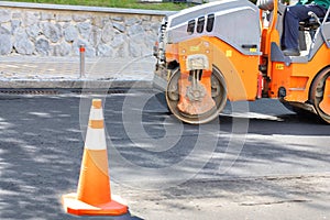 Road construction roller in motion rams fresh asphalt on the roadway