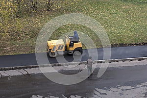 Road construction worker drives roller compactor machine