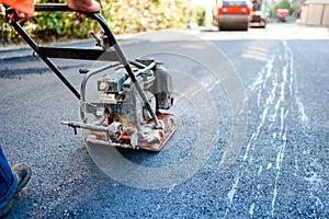 Road construction with worker paving the fresh bitumen or asphalt