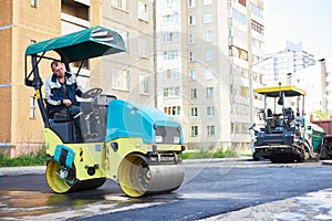 Road construction. Worker on steam vibration roller compacting asphalt