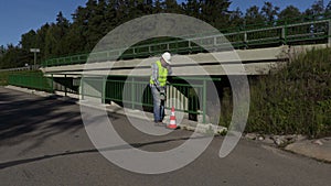 Road construction worker talking on phone on bridge near highway