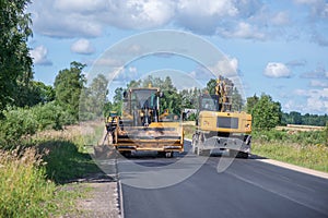 Road construction workers repairing highway road on sunny summer day