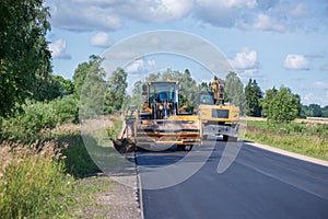 Road construction workers repairing highway road on sunny summer day