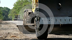 Road construction works, repair of a highway, The tractor is leveling gravel on the road, making a base for laying the