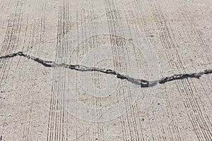 Road crack, surface of concrete driveway with crack and grass