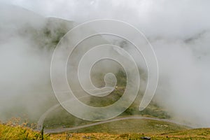 The road that crosses the Fagaras mountains seen from above among the fog, Transfagarasan, Romania