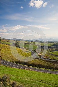 Road crossing beautiful countryside among green hills in Tuscany