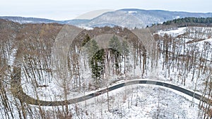 the road curves over a snowy valley in the mountains in this aerial photo