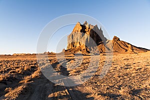 Road curving through a vast landscape to the rock formation of Shiprock in New Mexico