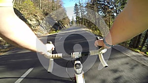 Road Cyclist POV. Male road cyclist riding his bicycle downhill on a asphalt road on a perfect sunny day