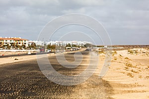 Road with desert on one side and a town on the other