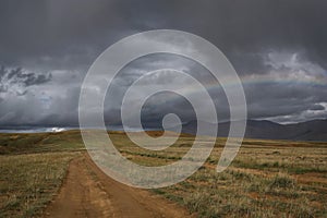 Road dirt steppe rainbow mountains clouds