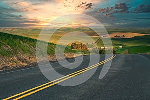 Road with dividing line in the countryside with colorful sunset in the distance