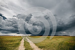 A road in the fields in front of stormy clouds