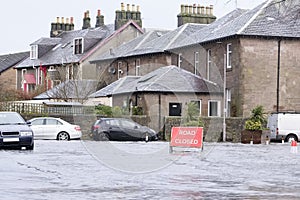 Road flood closed sign under deep water during bad extreme heavy rain storm weather in UK