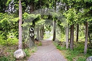 Road in forest with a no riding sign and a no vehicles sign