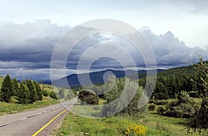 Road in forest under a blue sky with white clouds Sayan mountains Siberia Russia