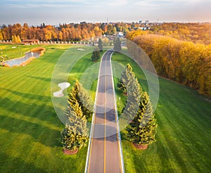 Road through the golf course at sunset in autumn. Aerial view