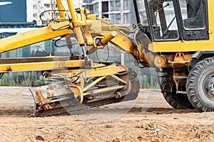 Road grader at the construction site. Powerful construction machine for ground leveling and excavation. Close-up. Professional