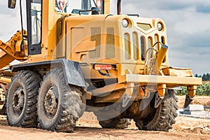 Road grader at the construction site. Powerful construction machine for ground leveling and excavation. Close-up. Professional