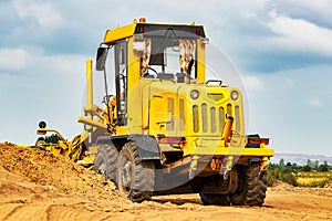 Road grader at the construction site. Powerful construction machine for ground leveling and excavation. Close-up. Professional