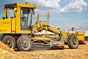 Road grader at the construction site. Powerful construction machine for ground leveling and excavation. Close-up. Professional